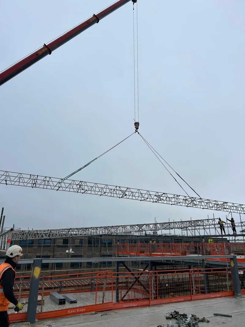 Crane boom and rigged lattice beam being landed on the temporary roof support scaffold