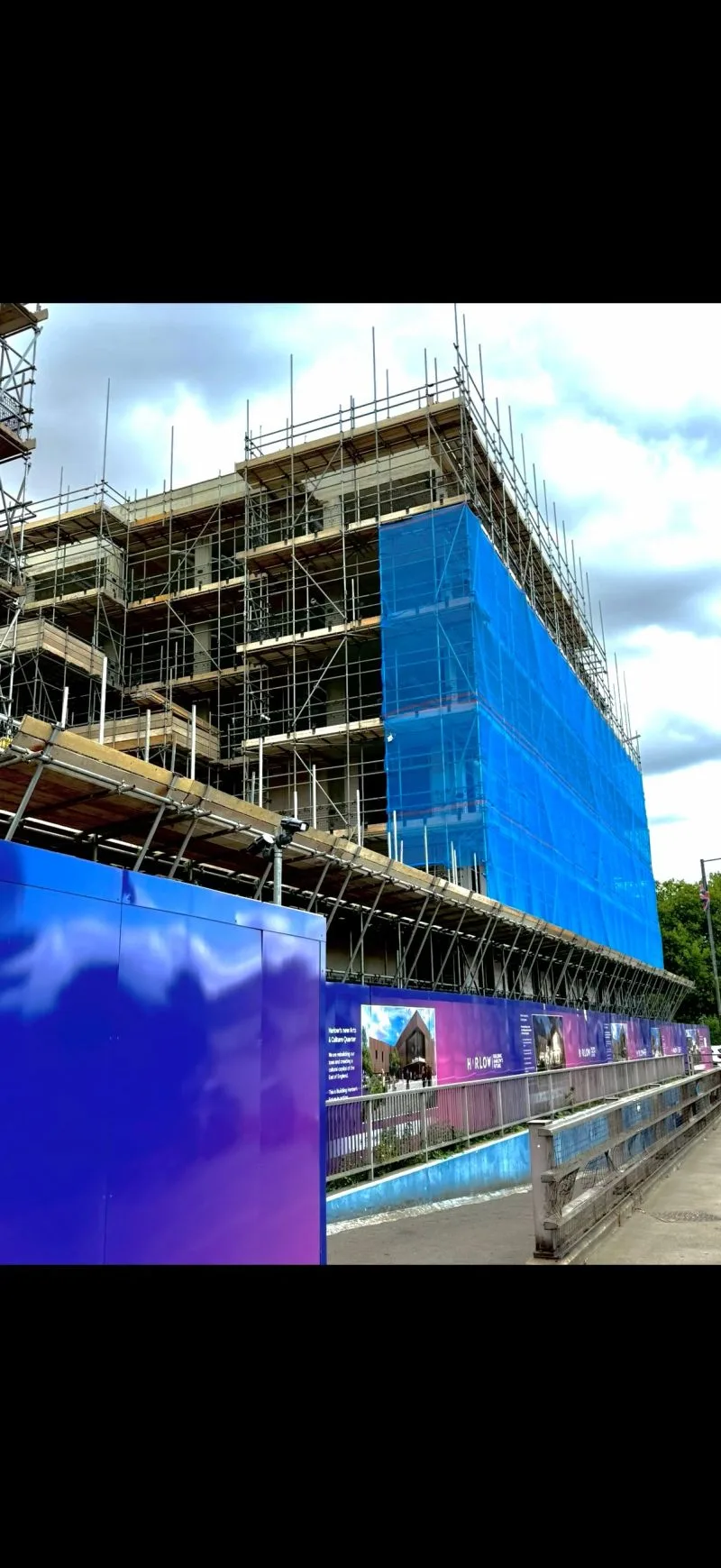Occasio House scaffold with debris netting on gable end and Harlow Playhouse Cultural Quarter hoarding