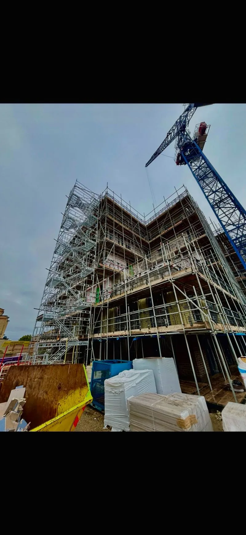 Occasio House full-perimeter access scaffold with tower crane between blocks